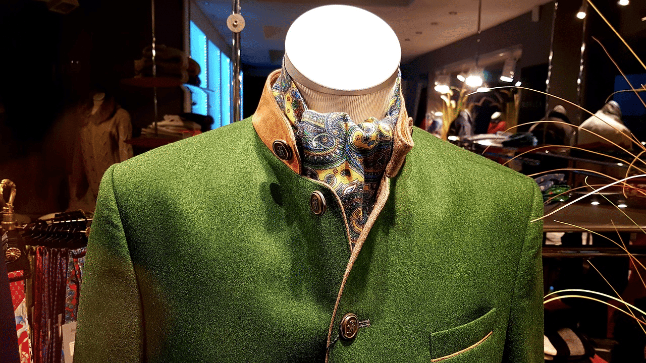 Mannequin in green coat with paisley scarf in a clothing store display.